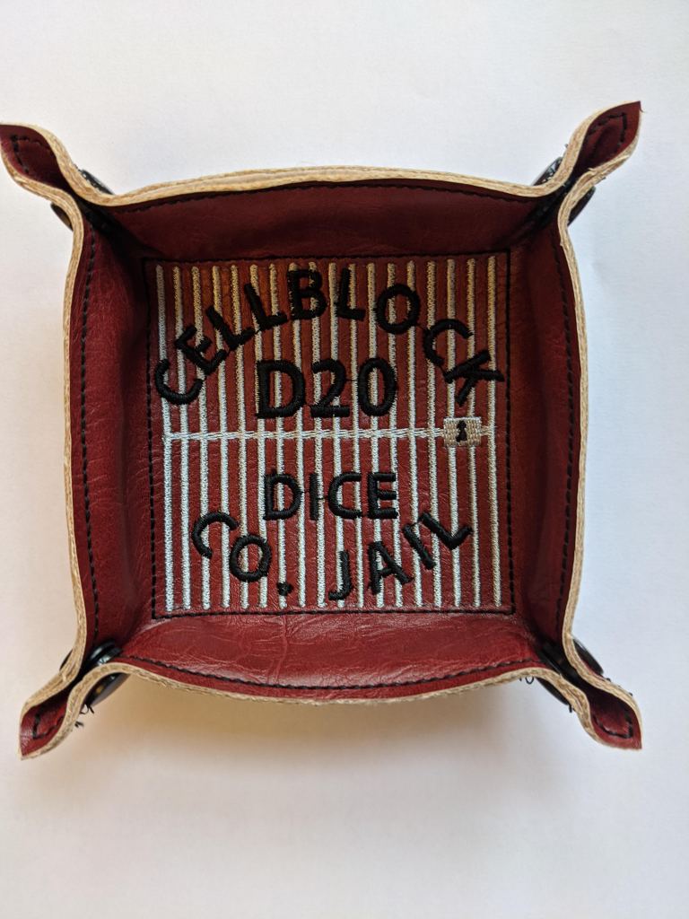 Dice tray shown in red vinyl with the words Cellblock D20 Dice County Jail.