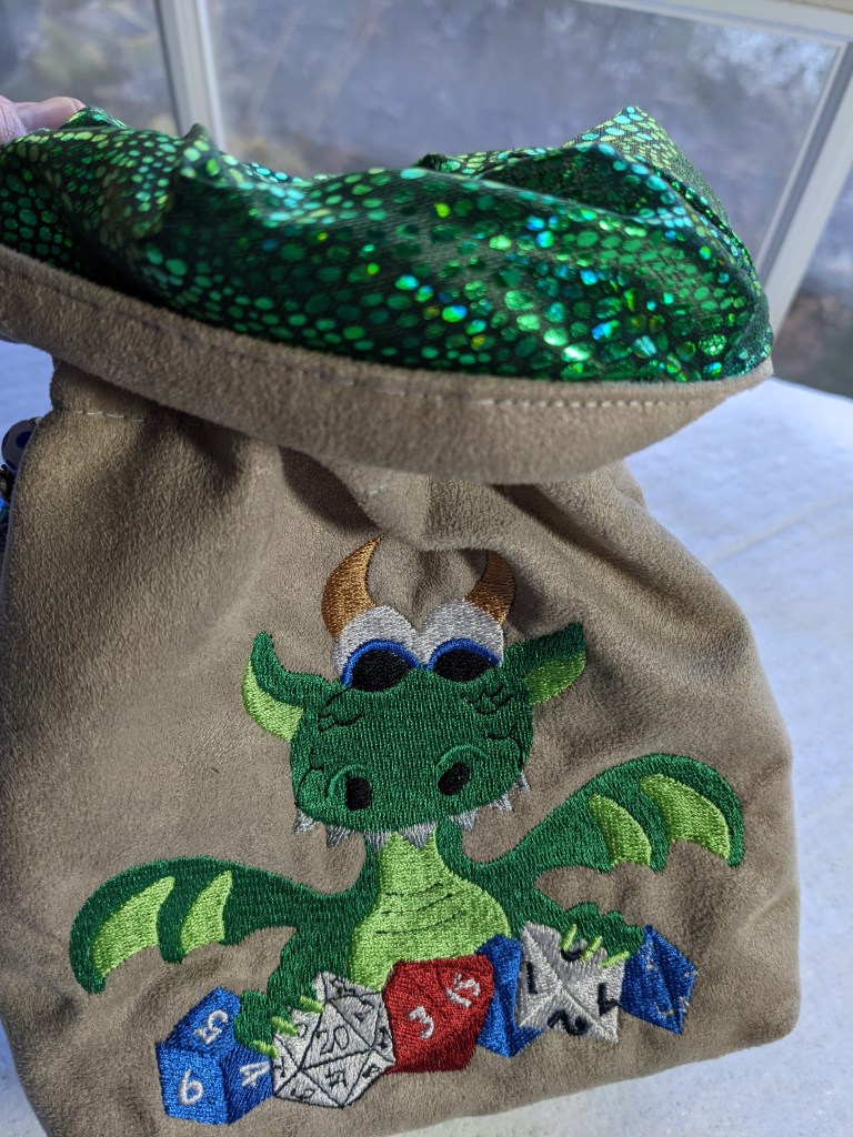 View of the tan dice bag showing a sparkly green lining fabric on the inside.