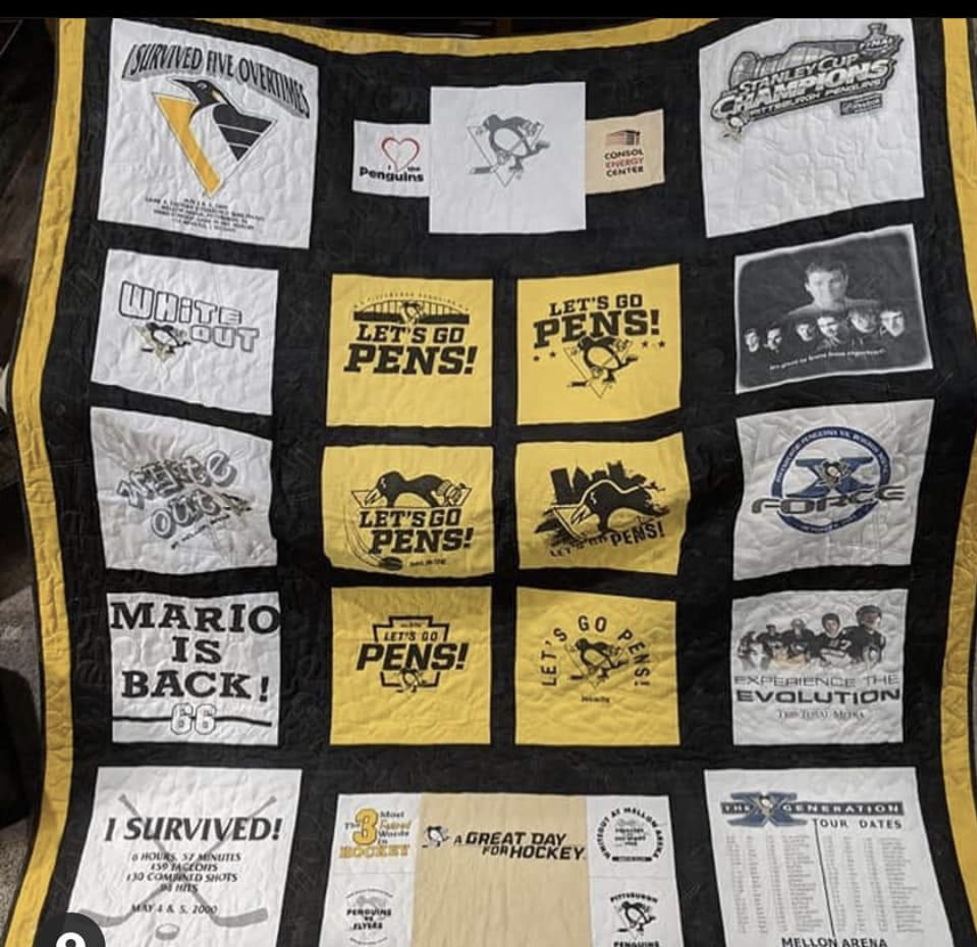 Picture of a t-shirt quilt made from Pittsburgh Penguins playoff tshirts.  Shirts are white and gold, and the quilt has black sashing, gold borders, and black binding.